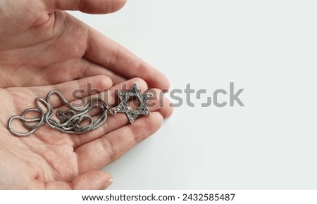 Opened hands palms with silver star of David pendant, judaism. Passover. Copy space.