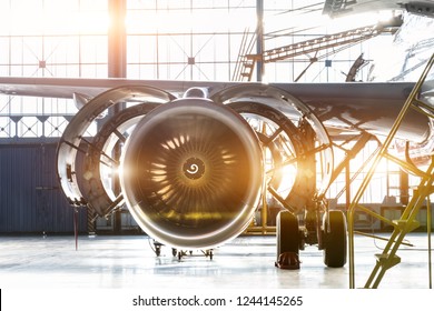 Opened Hood Airplane Engine Jet Under Maintenance In The Hangar ,with Bright Light Flare At The Gate