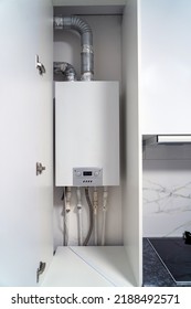 Opened Kitchen Cabinet And LPG Gas Boiler Inside Furniture. Gas Central Heating Condensing Boiler Fitted Inside Cabinet.