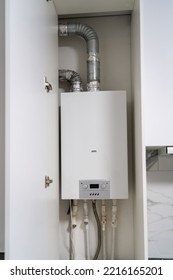 Opened Kitchen Cabinet And LPG Gas Boiler Inside Furniture. Gas Central Heating Condensing Boiler Fitted Inside Cabinet.