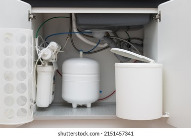 Opened Kitchen Cabinet With Sink, Installed Garbage Bin And House Water Filtration System. Kitchen Equipment