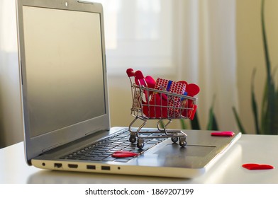 Opened laptop computer on the white  desk, shopping cart, decorative gift box, hearts. Concept of online-shopping for Valentine's day, international Women's day - Powered by Shutterstock