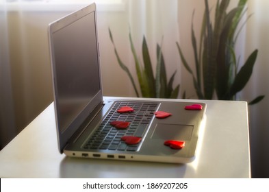 Opened laptop computer on the white  desk, shopping cart, decorative gift box, hearts. Concept of online-shopping for Valentine's day, international Women's day
