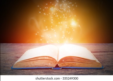 Opened magic book on abstract gold background 
