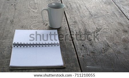 Opened notebook and ceramic mug on wooden table.  