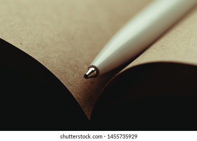 Opened notepad with automatic plastic ballpoint pen close up.