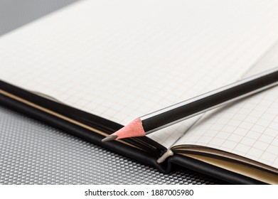 Opened notepad with pencil on gray background.