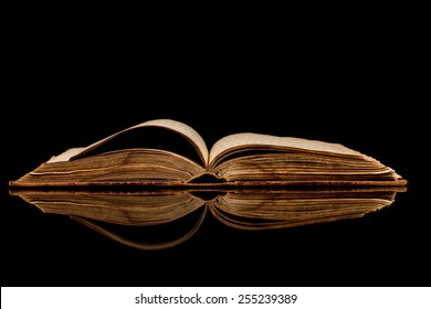 Opened old book with reflected in black surface