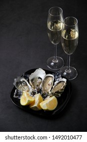 Opened oysters, ice and lemon on stone table. Oyster dinner with champagne in restaurant. Vertical