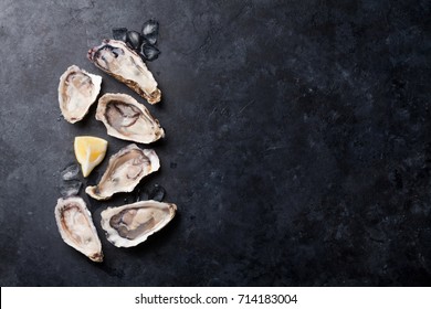 Opened oysters, ice and lemon on stone table. Half dozen. Top view with copy space