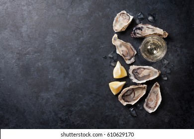 Opened oysters, ice and lemon with white wine over stone table. Half dozen. Top view with copy space