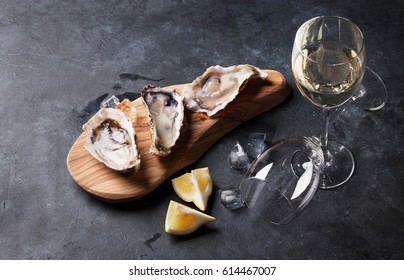 Opened oysters, ice and lemon and white wine on stone table