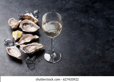 Opened oysters, ice and lemon with white wine over stone table. Half dozen. With copy space