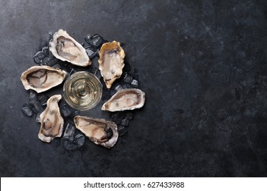 Opened oysters, ice and lemon and white wine on stone table. Top view with copy space