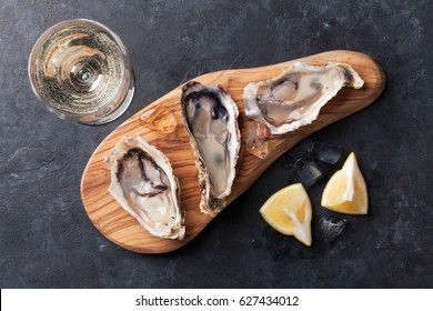 Opened oysters, ice and lemon and white wine on stone table. Top view