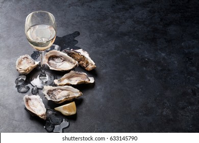 Opened oysters, ice and lemon with white wine over stone table. Half dozen. With copy space