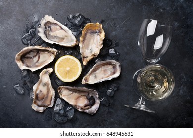 Opened oysters, ice and lemon and white wine on stone table. Top view