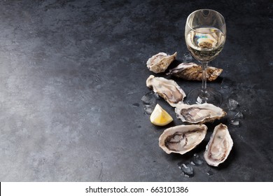 Opened oysters, ice and lemon and white wine on stone table. With copy space