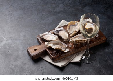 Opened oysters, ice on board and white wine on stone table. With copy space
