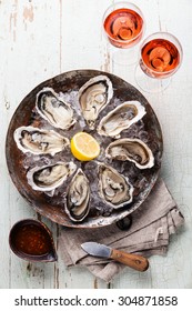 Opened Oysters on metal copper plate on blue wooden background with spicy sauce and wine rose