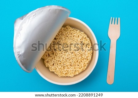 Opened Package with Uncooked Instant Noodles on Blue Background. Raw Pasta. Dry Asian Fast Food. Quick Lunch