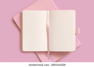 Opened pink notebook on on other one on light pink table top view. Textbook mockup, planner cover with place fot text. Educational, business and organizing concept