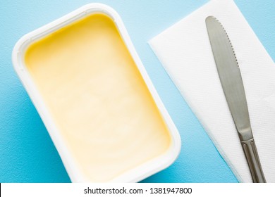 Opened Plastic Pack Of Light Yellow Margarine And Knife. Closeup. Pastel Blue Desk.