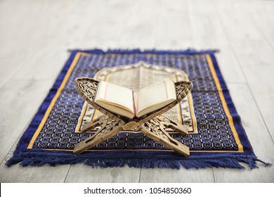 Opened Quran on Muslim prayer mat indoors
