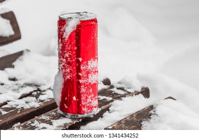 An Opened Red Shiny Bright Tin Can With White Snow On Its Surface With Key For Cool Cold Soft Drinks On A Wooden Brown Bench With White Snow For Cooling Like In The Fridge In Winter