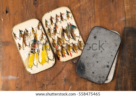 An opened Salmon fly box showing a selection of old salmon featherwing fishing flies circa 1900 and two closed boxes to the side