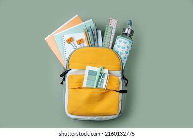 Opened School backpack with stationery  on green background. Concept back to school. School supplies.
