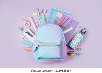 Opened School backpack with stationery in pastel color on pink background. Concept back to school. School supplies.