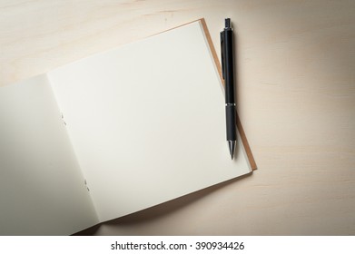 Opened Sketch Book With Blank Area For Text Or Message And Pen On Wood Table In Morning Time With Low Key Scene