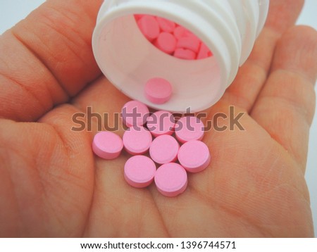 An opened tablet bottle on hand with pink tablets of warfarin sodium. Warfarin is a Vitamin K antagonist which is used for preventing the blood from clotting          