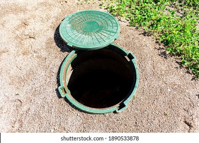 Opened unsecured sewer manhole of rural septic tank with green plastic cover, sewage system