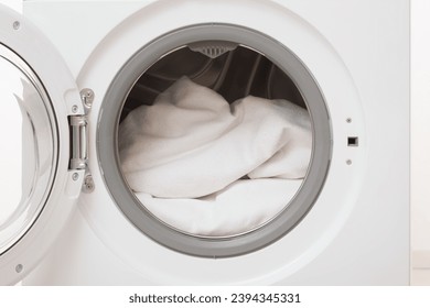 Opened washing machine full of white clothes. Closeup. Front view. - Powered by Shutterstock