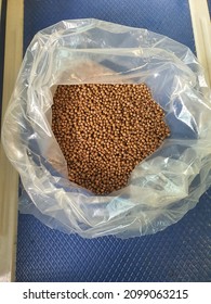 An opened white transparent plastic pack with dry fish feed pellet. 2mm size. Brown square round shape. Floating type feed. Freshwater and marine fish. Contain fish oil and fish meal. Smelly. Malaysia