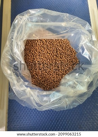 An opened white transparent plastic pack with dry fish feed pellet. 2mm size. Brown square round shape. Floating type feed. Freshwater and marine fish. Contain fish oil and fish meal. Smelly. Malaysia
