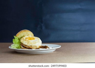 An open-faced sandwich with a fried egg, lettuce, and sauce on a white plate. - Powered by Shutterstock