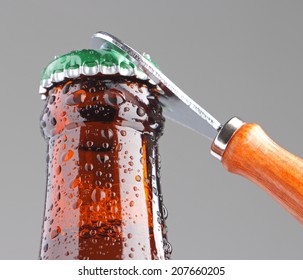 Opening Beer Bottle With Bottle Opener In Grey Background
