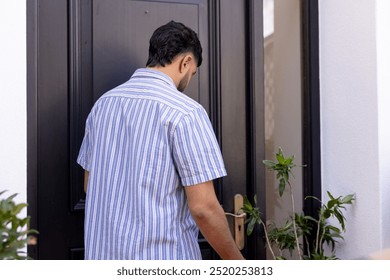 Opening door, man entering home, wearing striped shirt, back view. arriving, casual, indoors, lifestyle, entrance, doorway - Powered by Shutterstock