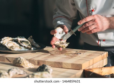 Opening the hollow and flat oysters. Chef opens oysters in the restaurant