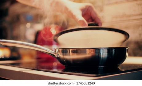 Opening Hot Sizzling Steel Fry Pan On Stove Top. Cooking At Home