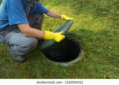 Opening septic tank lid. Cleaning and unblocking septic system and draining pipes.