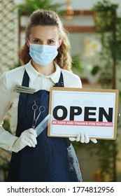 Opening Small Business After Coronavirus Pandemic. Modern Hair Salon Worker In Apron With Medical Mask, Gloves, Hair Comb And Scissors Showing Welcome Sign.