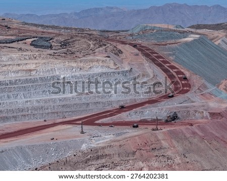 Open-pit mining operations process with excavator extracting and loading minerals into mining dump trucks
