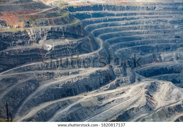 Open-pit mining raw minerals for steel production.\
Giant iron ore quarry in Rudny, Kazakhstan. Yellow quarry truck\
down. Quarry steps under\
sun.