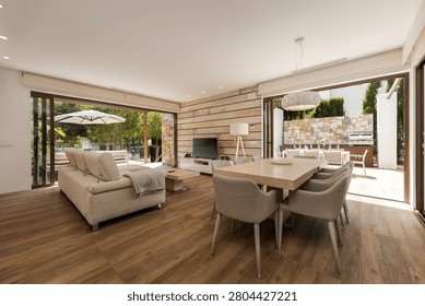 Open-plan living and dining area with sofas, a dining table, and sliding doors opening to a terrace