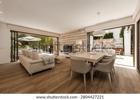 Open-plan living and dining area with sofas, a dining table, and sliding doors opening to a terrace