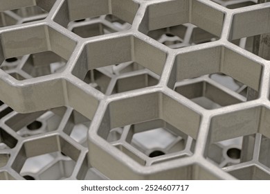 Openwork three-dimensional metal grid with hexagonal cells. Close up shot, abstract metalwork industry background.